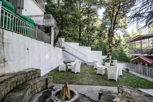 a patio with white chairs and tables and stairs at The Bunksters Mcleodganj, Dharmkot in McLeod Ganj