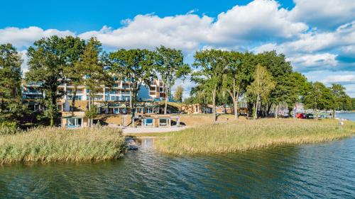 a body of water with trees and a building at Stranda in Giżycko