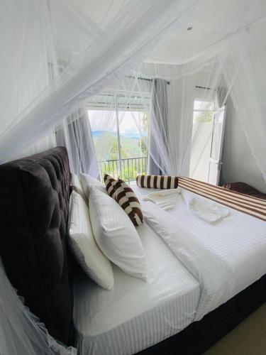 a white bed with white pillows and a window at Ella Nimal Nest Inn in Ella