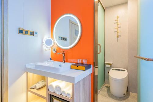 an orange bathroom with a sink and a mirror at Dequan Luxury HotelGuomao BranchThe subway is right outside the door Coffee, fruits, snacks, a gym and a laundry room are provided for free in the lobby in Beijing