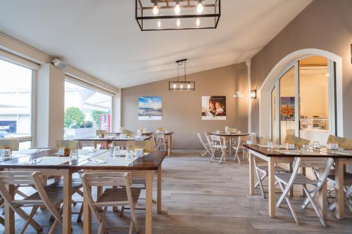 a restaurant with wooden tables and chairs and windows at Club del Sole Vigna sul Mar Family Collection in Lido di Pomposa