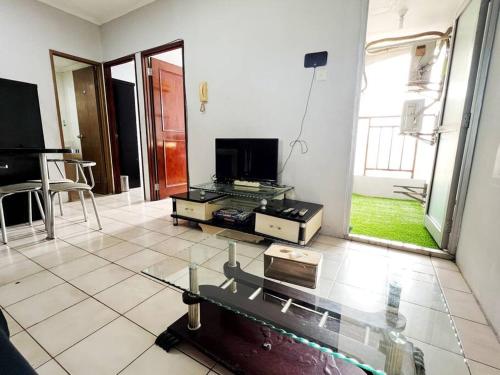 a living room with a television and a tiled floor at Cozy Central Jakarta Apartment in Jakarta