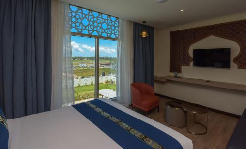 a hotel room with a bed and a large window at Golden Tulip Zanzibar Airport Hotel & Spa in Zanzibar City
