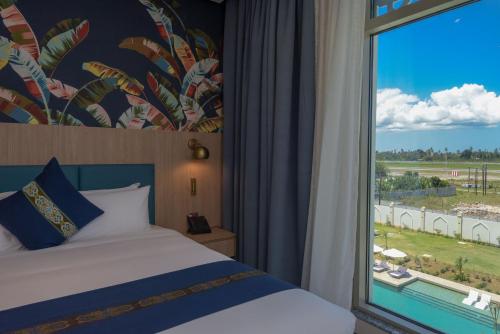 a bedroom with a bed and a large window at Golden Tulip Zanzibar Airport Hotel & Spa in Zanzibar City