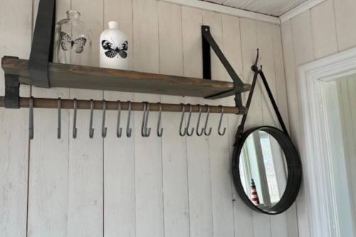 a mirror on a wall with a shelf and scissors at B & B Hjärthuset Zweden Ekshärad in Ekshärad
