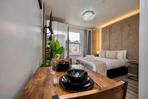 a room with a bed and a wooden table with bowls and plates at Gilded Nooks in Croydon