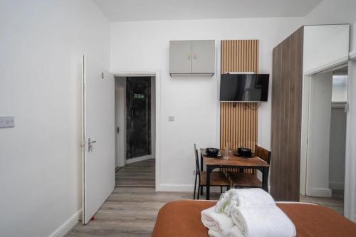 a room with a bed and a table and a kitchen at Gilded Nooks in Croydon