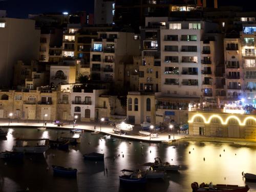 a city at night with boats in the water at Unique Seaview Apartments and Penthouse in Central St Julians in St Julian's