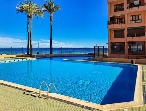 Una gran piscina con palmeras y un edificio. en EL AQUARIO - Urbanización Eurovosa VISTAS AL MAR 1 DORMITORIO, en La Manga del Mar Menor