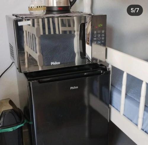 a microwave oven sitting on top of a refrigerator at Quarto Familiar Sil Cardoso in Blumenau