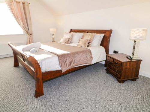 a bedroom with a large bed and a night stand at SJs Cottage in Coleraine