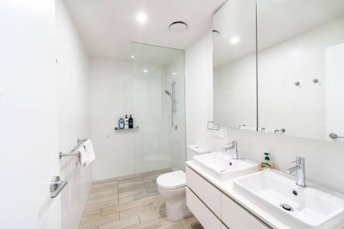 a white bathroom with two sinks and a toilet at Central 2BR-2BA Resort-Style Retreat In Hamilton M21 in Brisbane