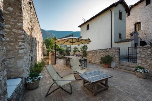 a patio with an umbrella and a table and chairs at Relais Borgo Campello in Campello sul Clitunno