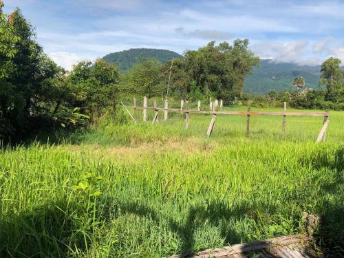 a wooden fence in a field with grass at Mountain View House Kampot in Kampot