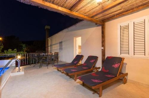 a group of chairs sitting on a patio at night at Tranquil Villa with Pool in Gruda