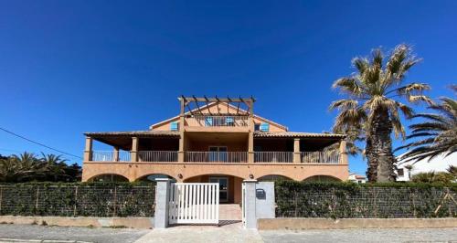 une grande maison avec une clôture et un palmier dans l'établissement Beach Nest, à Hyères