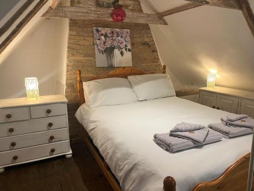 a bedroom with a bed with two towels on it at 15th Century Thatched Cottage in Cambridge