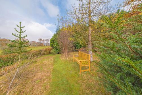 a wooden bench sitting in the middle of a field at Hollace, Lake District bungalow with hot tub and stunning views in Coniston