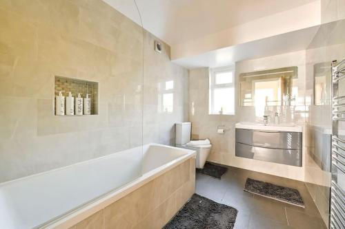 a bathroom with a tub and a toilet and a sink at House with Garden Next Wembley Stadium Free Parking in London