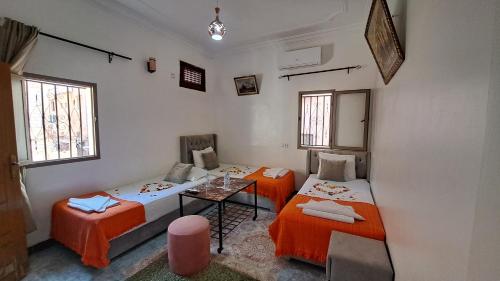 a room with two beds and a table and windows at Hotel Riad Fantasia in Marrakech