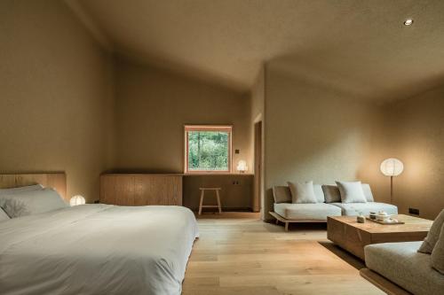a bedroom with a bed and a couch and a table at 大山初里 Origin Villa Village Hotel&Resort in Tonglu