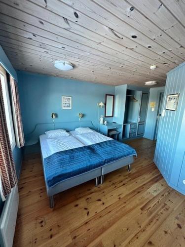 a bedroom with a bed with blue walls and wooden floors at Rauland Høgfjellshotell in Rauland
