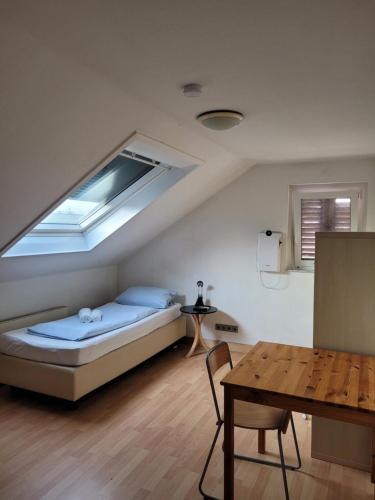 a bedroom with a bed with a window and a table at Pension Urbanstraße 46 in Stuttgart