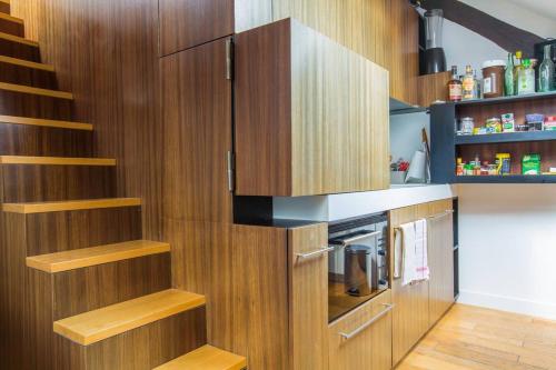 une cuisine avec des placards en bois et un escalier dans l'établissement Small Triplex, à Paris