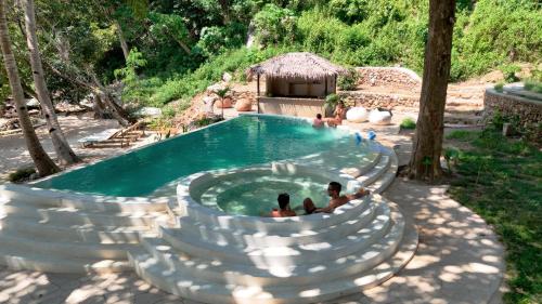 a swimming pool with people sitting in the water at Parada Beach Camp in El Nido