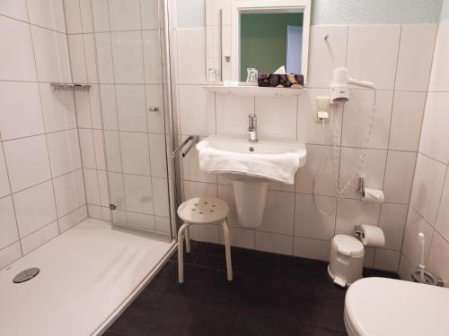 ein weißes Bad mit einem Waschbecken und einer Dusche in der Unterkunft Hotel Zum Herrenhaus in Behringen