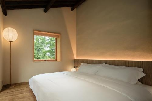 a bedroom with a white bed and a window at 大山初里 Origin Villa Village Hotel&Resort in Tonglu