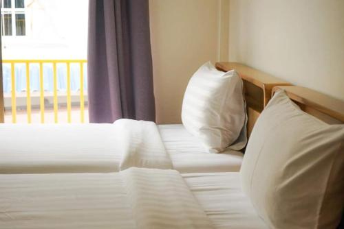 a bedroom with a bed with two pillows and a window at Sidewalk Boutique Hotel in Ko Samed