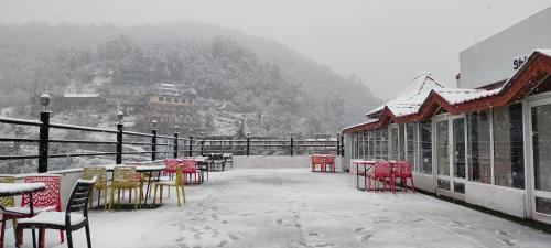 a patio with tables and chairs in the snow at Regenta Resort MARS Valley View Shoghi in Shimla