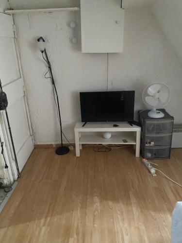 un salon avec une télévision et un bureau avec une lampe dans l'établissement Djawed, à Paris