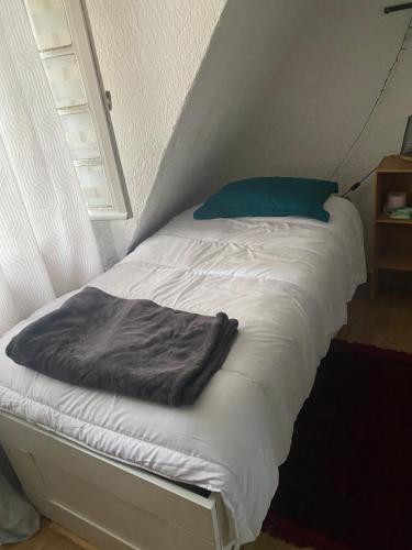 - un lit avec des draps blancs et un oreiller bleu dans l'établissement Djawed, à Paris