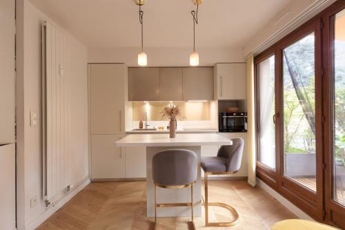 a kitchen with a white counter and a table and chairs at Charmant Appart, terrasse verdoyante, proche Paris in Saint-Maur-des-Fossés
