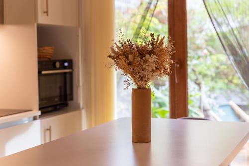 a vase with flowers on a table in a kitchen at Charmant Appart, terrasse verdoyante, proche Paris in Saint-Maur-des-Fossés