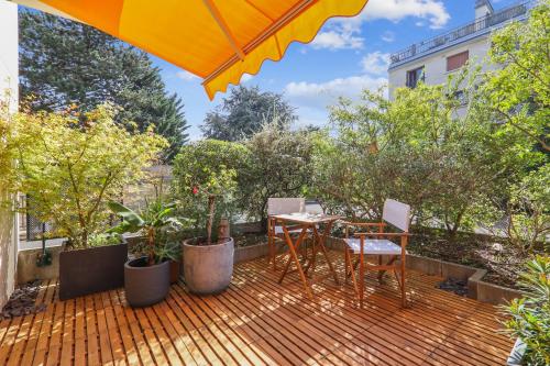 a patio with a table and chairs and an umbrella at Charmant Appart, terrasse verdoyante, proche Paris in Saint-Maur-des-Fossés