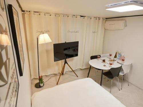 a room with a bed and a table and a tv at Warm Place in Seoul