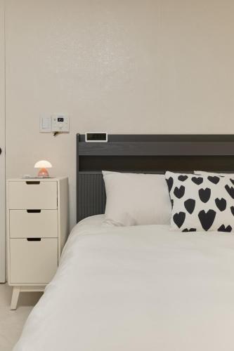 a bedroom with a white bed and a white nightstand at Warm Place in Seoul