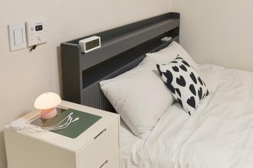 a white bed with a black headboard and a night stand at Warm Place in Seoul