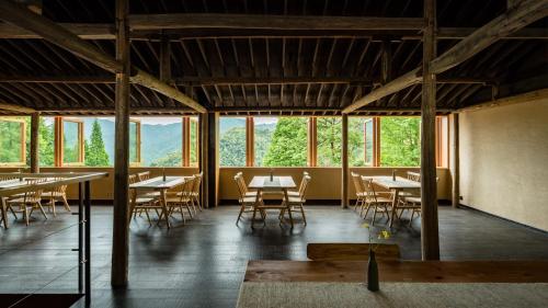 a dining room with tables and chairs and windows at 大山初里 Origin Villa Village Hotel&Resort in Tonglu