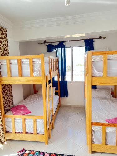 a room with three bunk beds and a window at Locals Taghazout surfcamp in Taghazout