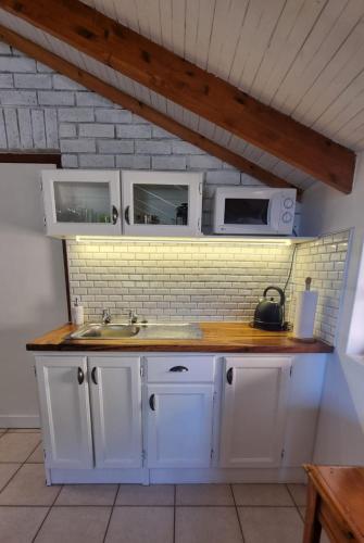 a white kitchen with a sink and a microwave at The Sculpture Yard in Gordonʼs Bay