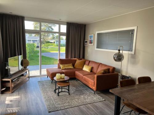 a living room with a brown couch and a table at Cube 8 - Neues Ferienhaus im Ferienpark am Badesee in Lathum