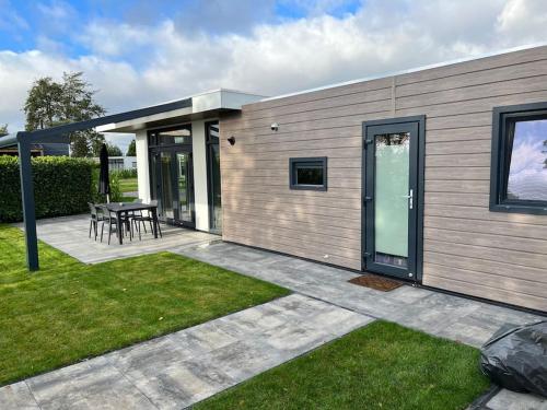 a small house with a patio and a table at Cube 8 - Neues Ferienhaus im Ferienpark am Badesee in Lathum