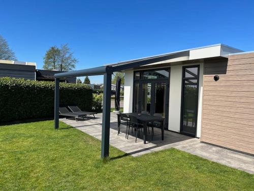 a patio with a black table and chairs on the grass at Cube 8 - Neues Ferienhaus im Ferienpark am Badesee in Lathum