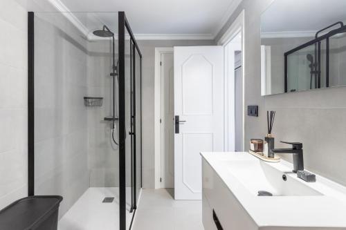 a white bathroom with a sink and a shower at Luxe 6 pers strand app met zeezicht en zwembad Arenal Beach in Platja de l'Arenal