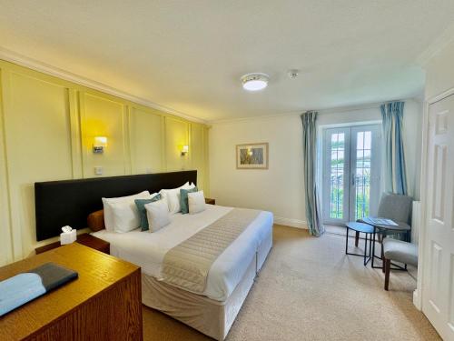 a hotel room with a large bed and a desk at The White House Hotel in Herm