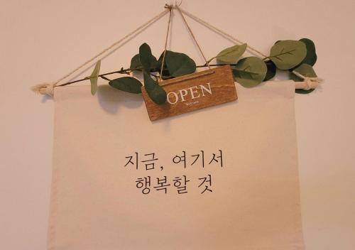 a sign that says open with a plant on a wall at Hey, World Stay SEOUL in Seoul